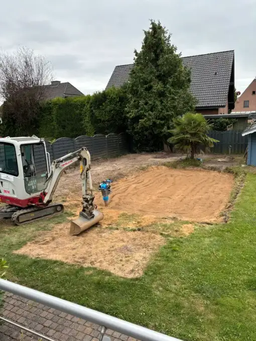 Minibagger mit Rüttelplatte auf einer planierten Fläche im Garten