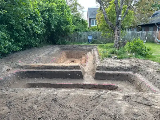 Ausgehobene Grube für einen Pool mit Stufen in einem Garten